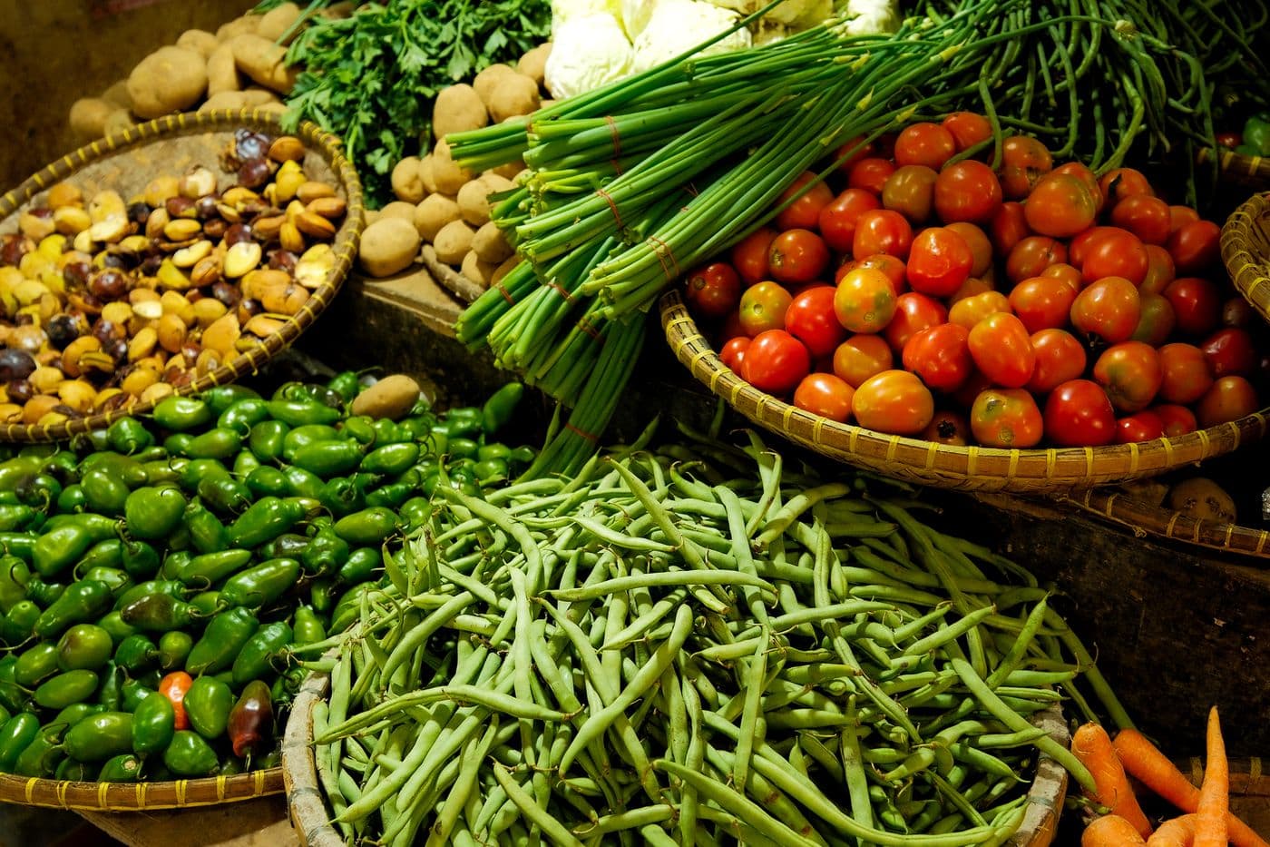 Canastas con tomates, vainitas, ajíes y verduras frescas en un mercado