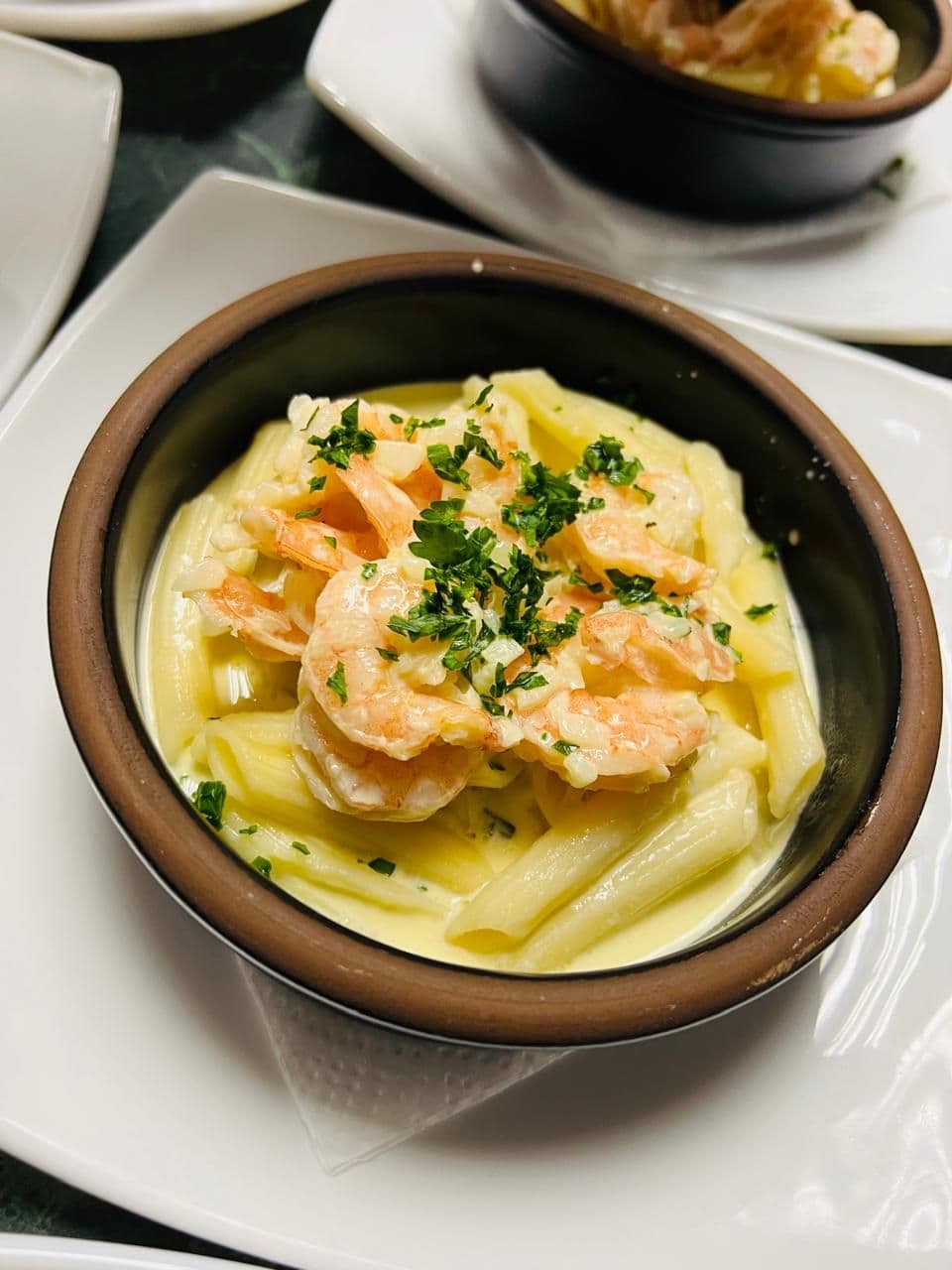 Pasta con camarones servida en cazuela de barro