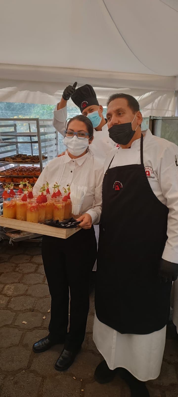 Equipo de Tomillo & Laurel con mascarilla sirviendo una bandeja de postres en un evento